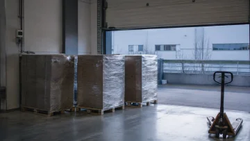 Drie gewikkelde pallets bij een open laaddeur met een palletwagen
