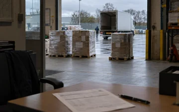 Ingepakte pallets klaar op de laadkade, met een orderformulier op het bureau ervoor