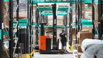 Medewerker met een reachtruck tussen gevulde magazijnstellingen